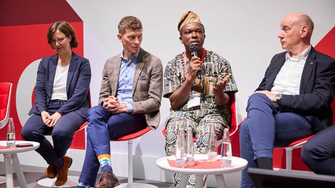Panel discussion with four participants, one speaking into a microphone.