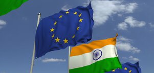 The flags of India and the European Union fly against a blue sky with scattered clouds.