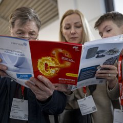 Three people reading brochures during the ceramitec trade fair.