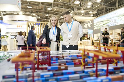 Eine Frau und ein Herr studieren auf der Messe ein Logistik- und Transportmodell für Umschlagbahnhöfe.