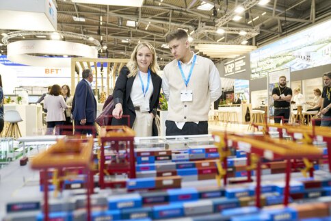 A woman and a man study a logistics and transportation model for transshipment terminals at the trade fair.