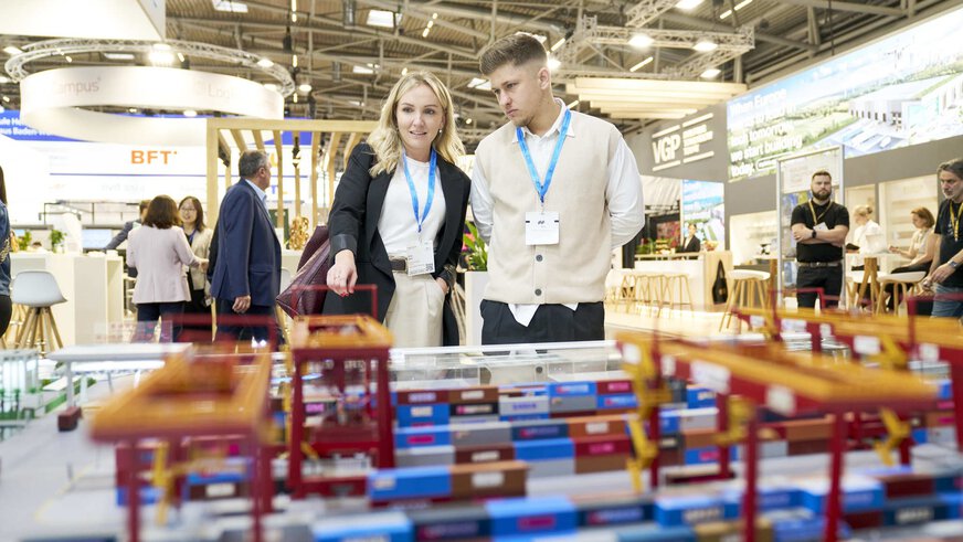 Eine Frau und ein Herr studieren auf der Messe ein Logistik- und Transportmodell für Umschlagbahnhöfe.