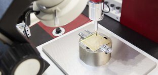 Bild von der productronica, eine Nahaufnahme eines Messtasters, der über einer fixierten Plakette schwebt.