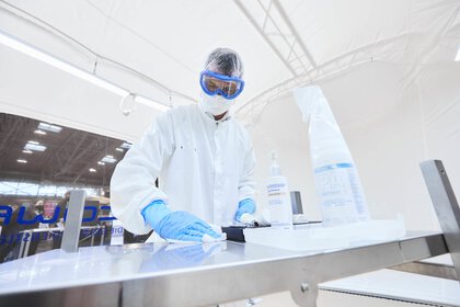 Eine Person in voller Schutzausrüstung reinigt eine Oberfläche in einer Laborumgebung auf der productronica.