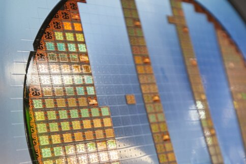 Close-up of a computer silicon wafer. Some of the chips are coated with a reflective, bluish shimmering surface.