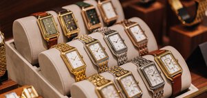 A display case with luxury wristwatches with metal and leather straps in various colors.