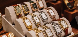 A display case with luxury wristwatches with metal and leather straps in various colors.