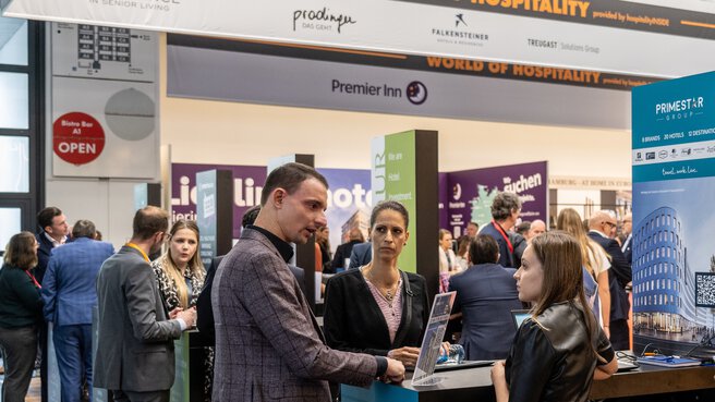 Drei Personen unterhalten sich an einem Messestand im Bereich 