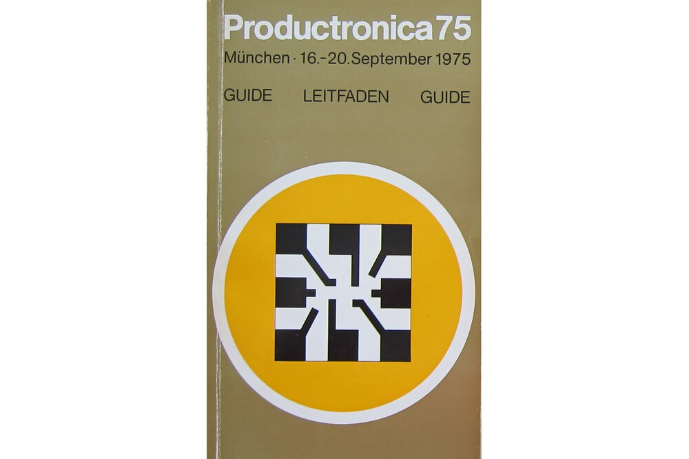 Ein Katalog zur productronica 1975 in brauner Farbe. In der Mitte ist ein schwarz-weißes Viereck in einem gelben Kreis mit weißem Rand zu sehen.