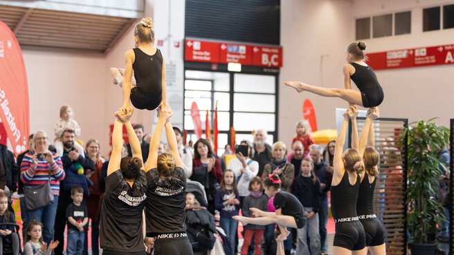 A gymnastics performance by young girls in front of an enthusiastic audience.