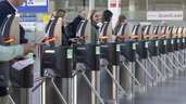 Lächelnde Menschen gehen durch die automatischen Ticketschranken am Messe Eingang.
