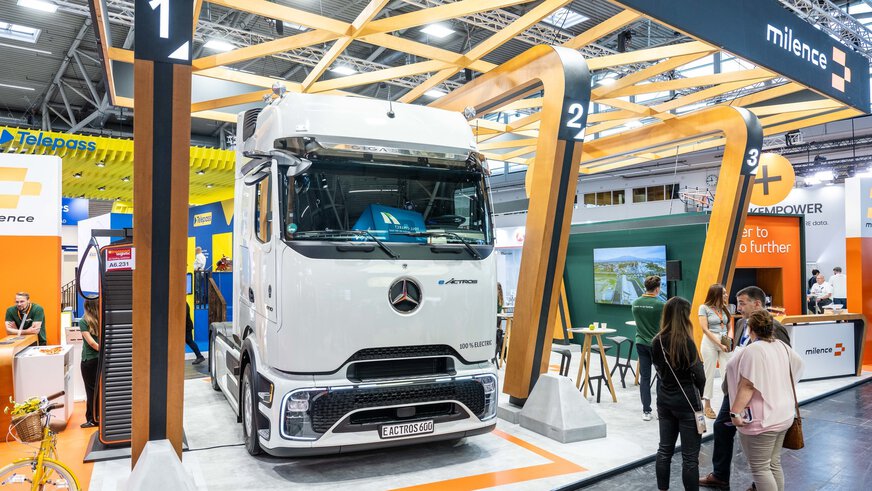 Ein großer weißer Truck von Mercedes Benz steht in der Mitte des Messestande von milence. Der Truck heiß eEACTROS 600 und ist elektrisch.