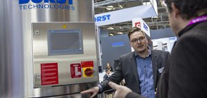 Two men in suits talking in front of a 