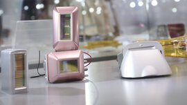 Several compact optoelectronic sensor modules with rectangular housings and visible color filters are displayed on an exhibition surface.