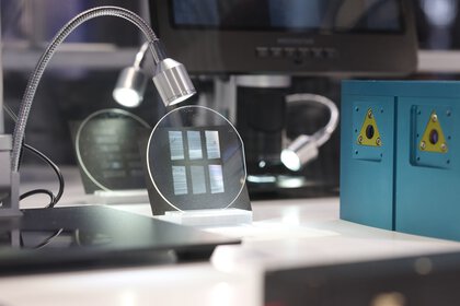 Close-up of a laboratory setup for optical communication technology: round glass plates with fine structures can be seen under selective lighting.