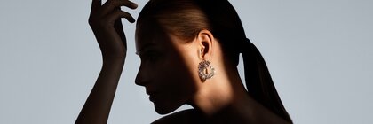 The silhouette of a woman with a ponytail sitting in the shade. Her diamond earring is illuminated by a ray of light.