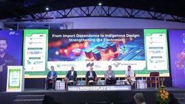 Industry leaders participate in a panel discussion at electronica India and productronica India. Five speakers are seated on stage beneath a large screen highlighting indigenous electronics design and innovation