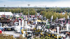 Luftaufnahme des INTERFORST-Messegeländes mit Forstmaschinen, Nutzfahrzeugen, Ausstellungsständen und zahlreichen Besuchern.