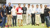 Eine Gruppe von Männern posiert mit Urkunden bei einer Siegerehrung auf der World of Quantum 2025 in München und zeigt Daumen hoch.