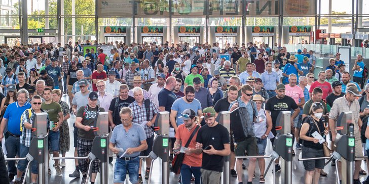  Eine große Menschenmenge wird durch Drehkreuze in einer Halle oder einem Kongresszentrum eingelassen.