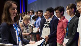 At an event, people stand in a row on the stage and accept certificates.