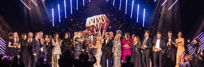Numerous people in festive attire stand cheerfully on the stage of the INHORGENTA AWARD ceremony while confetti rains down.