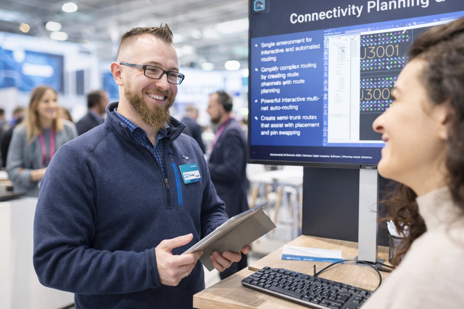 Conversation between exhibitor and attendee at a DMEA booth with digital solutions displayed on a screen