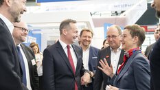 Eine Gruppe von Menschen in Geschäftskleidung unterhält sich lächelnd auf der transport logistic.