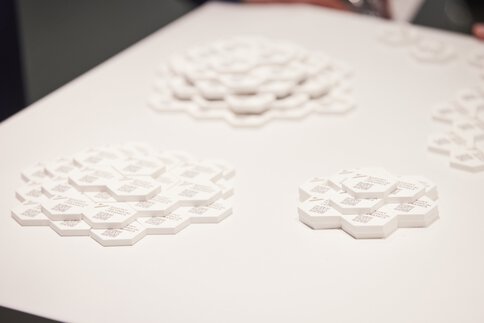 Three white, layered, hexagonal 3D shapes on a flat surface.