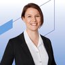 Portrait of a woman with short dark brown hair wearing a black blazer and white blouse in front of a light background with blue graphic lines