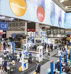 Vogelperspektive über den Innenraum einer gut besuchten Ausstellungshalle der transport logistic mit zahlreichen Plakaten, Ständen und Networking-Möglichkeiten.