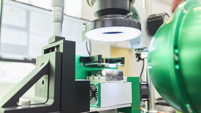 Eine Präzisionswerkbank mit Vergrößerung, einer grünen Metallverkleidung, einer hellen ringförmigen LED-Beleuchtung und aktiver Kühlung.