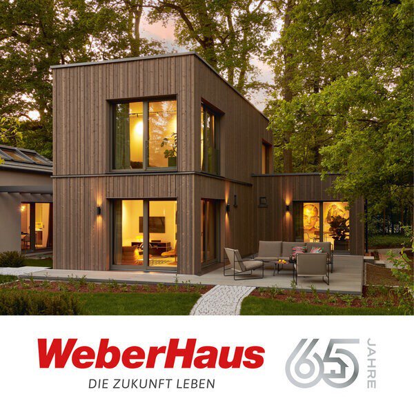 Modernes zweistöckiges Haus mit großen Fenstern und Terrasse, umgeben von Bäumen. WeberHaus 65 Jahre Logo unten.