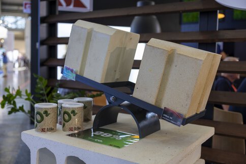 Two large bricks are presented on a black stand next to ceramic cups with 