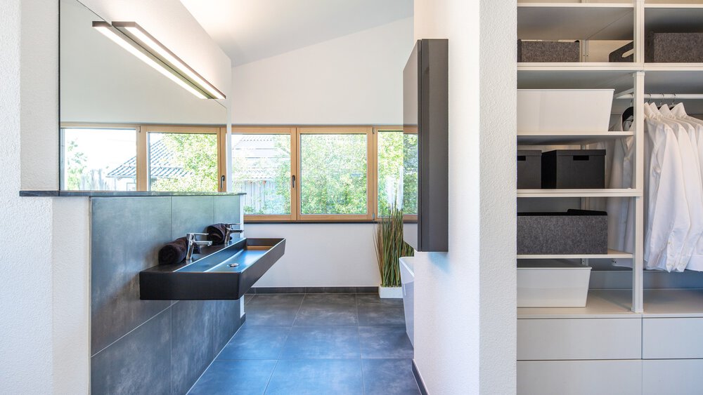 Minimalistische Küche mit weißen Schränken, großen Fenstern und modernen Geräten. Blaue Kücheninsel mit Hockern.