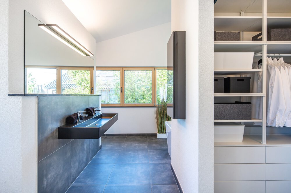 Minimalistische Küche mit weißen Schränken, großen Fenstern und modernen Geräten. Blaue Kücheninsel mit Hockern.