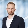 Man with short hair and beard in a suit.