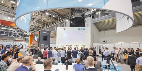 Speakers and visitors on the i_space stage during a panel discussion.