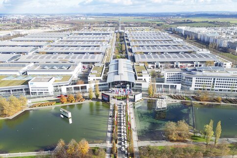 Aerial view of the Messesee with access to the West Entrance, as well as the exhibition halls and the Messeturm in the distance.