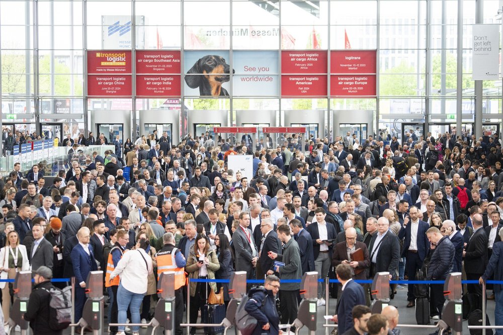 Zahlreiche Besucher warten auf den Einlass. Über den Eingängen hängen die Veranstaltungstermine der internationalen transport logistic-Messen.