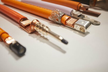 Nahaufnahme von orangenen Hochspannungskabeln mit unterschiedlichen Anschlüssen.