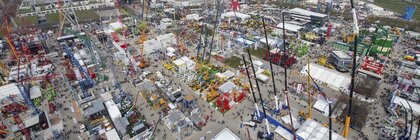 Aerial view of bauma with many stands, construction machines and cranes on the grounds of Messe München.