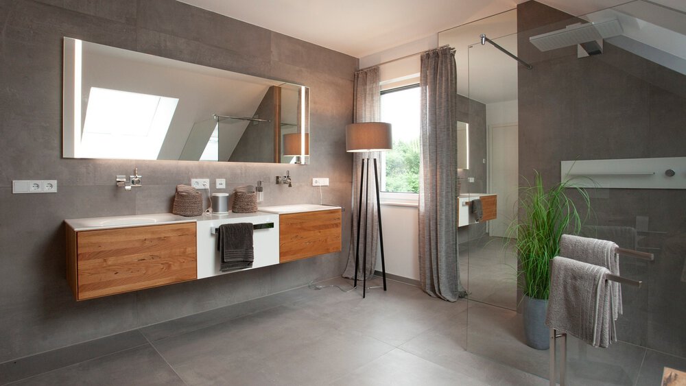 Modernes Badezimmer mit dunklen Fliesen, Holzschränken, großem Spiegel und Oberlichtfenster.