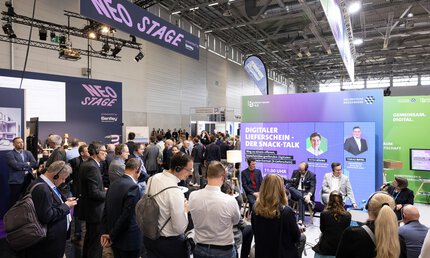 Besuchende stehen vor Screen und hören über Kopfhöpfhörer einer Panel-Diskussion zu. Hintergrundscreen mit dem Titel: Digitaler Lieferschein - der Snack-Talk