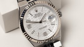 Close-up view of a wide silver angular wristwatch with a serrated edge and a dial with a scaly background.