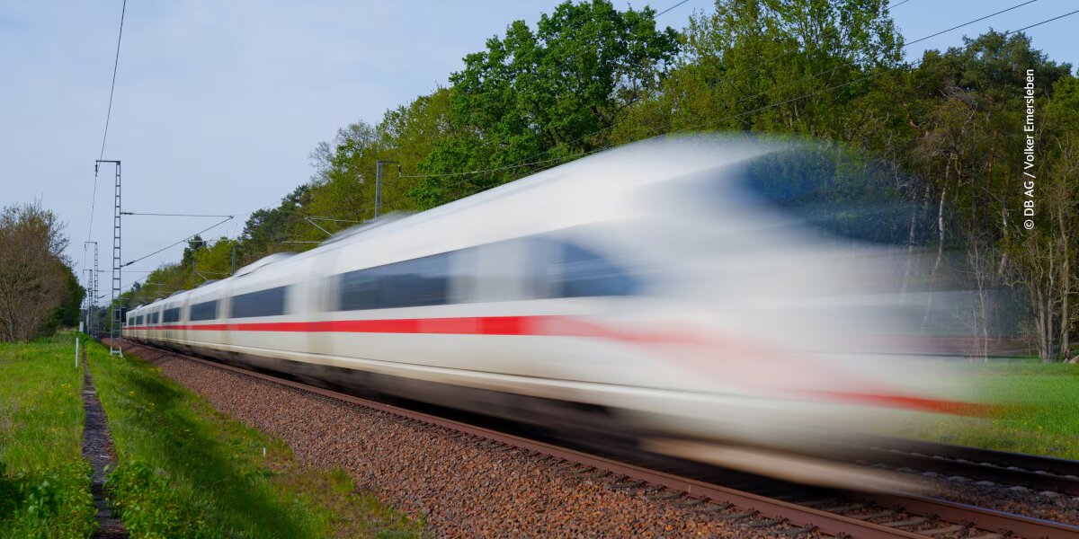 A white and red Deutsche Bahn train is traveling at high speed on a railway line
