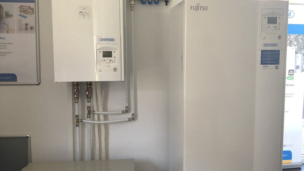 Aufbau eines HVAC-Systems in einem Ausstellungsraum mit Fujitsu-Einheiten und sichtbaren Rohren vor einer weißen Wand.