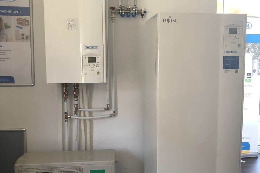 Aufbau eines HVAC-Systems in einem Ausstellungsraum mit Fujitsu-Einheiten und sichtbaren Rohren vor einer weißen Wand.