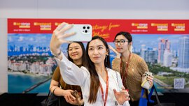 Drei Messebesucherinnen lächeln gemeinsam für ein Selfie vor einer Fotowand der transport logistic Messe.