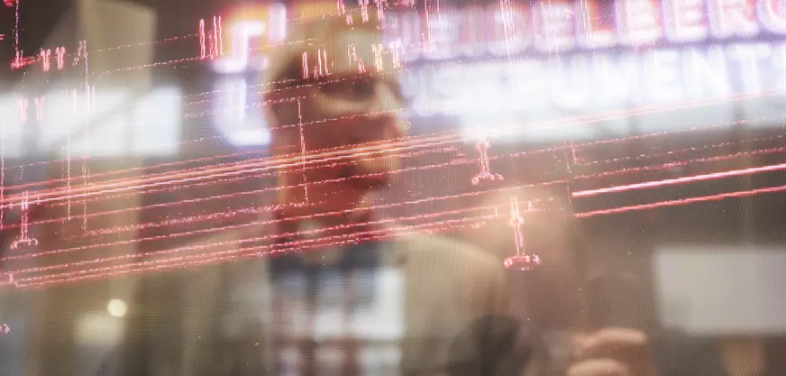 Reflection of two men on a pane of glass with red digital patterns and blurred text in the background.